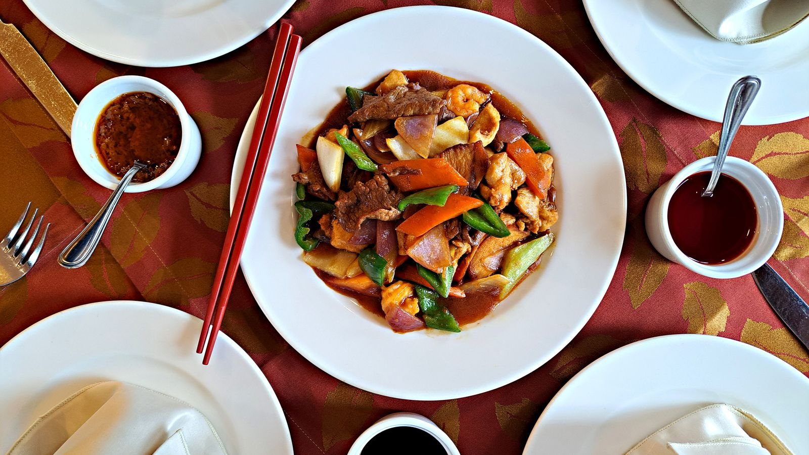 Farfurie cu stir-fry asiatic cu vită și legume colorate, servită pe o masă de restaurant