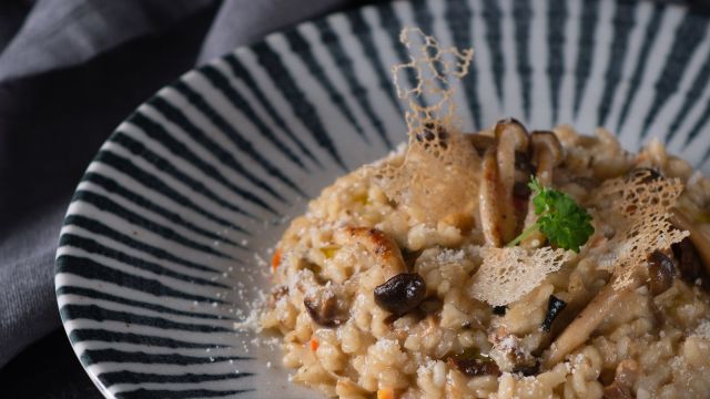 Risotto cu ciuperci, parmezan și pătrunjel, servit pe o farfurie decorativă.