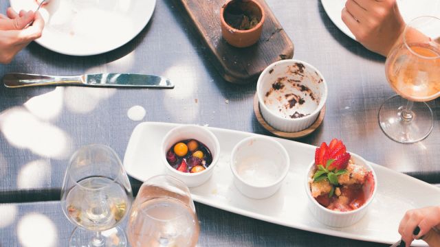 Vedere de sus a unei mese de restaurant pregătite pentru mai multe persoane, cu farfurii și platouri pentru servit în comun