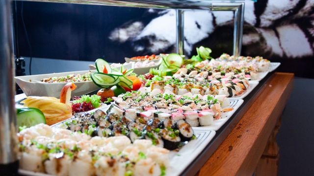Platou cu sushi pe farfurii albe, pe o masă de lemn maro
