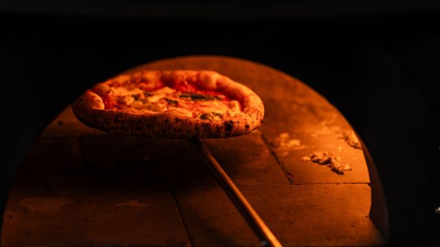 Pizza bagata in cuptor de catre un bucatar.