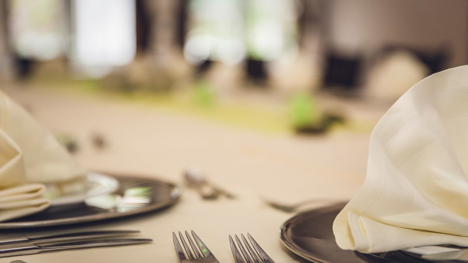 Masă de restaurant aranjată elegant, cu tacâmuri, pahare și șervete împăturite